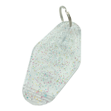 Detailed angle shot of translucent white with rainbow glitter motel-style keychain with Oaklandish Logo and 510 local love.