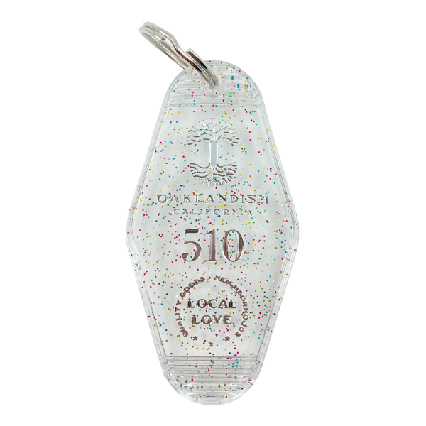 Translucent white with rainbow glitter motel-style keychain with Oaklandish Logo and 510 local love.