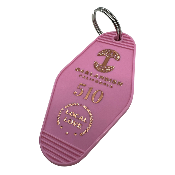 Detailed angle image of Pink vintage motel-style keychain with gold Oaklandish Logo and wordmark and 510 local love logo.