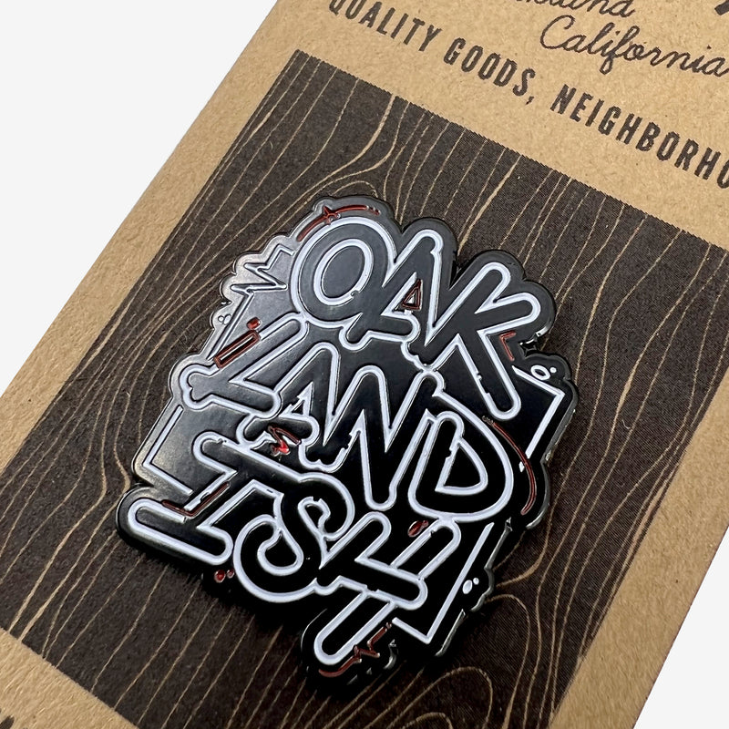 Close-up of black and white “Oaklandish” wordmark on an enamel lapel pin.