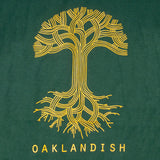 Close-up of a large yellow Oaklandish tree logo on the chest of a forest green t-shirt.