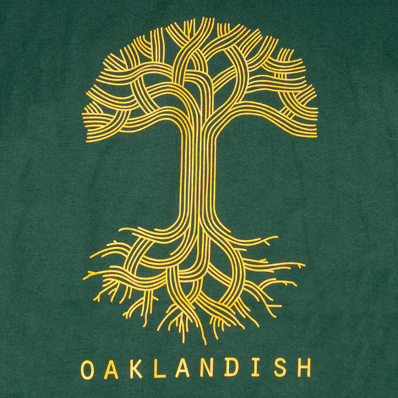 Close-up of a large yellow Oaklandish tree logo on the chest of a forest green t-shirt.