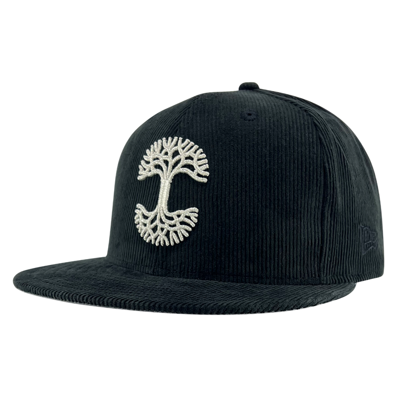 New Era black corduroy fitted cap with silver embroidered Oaklandish tree logo - angled to show New Era logo on left wear side.