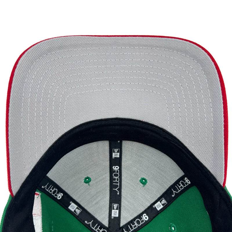 Gray undervisor and view inside crown of a green cap with black taping with black 9FORTY taping and New Era wordmarks on repeat.