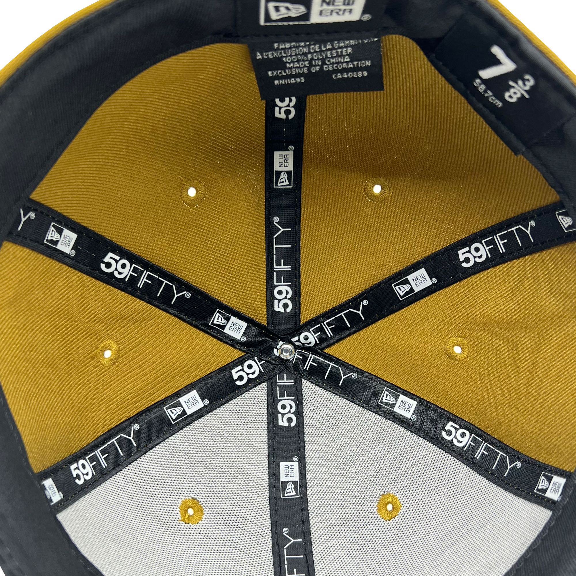 The image shows the inside of a New Era Official 59FIFTY Fitted Cap by Oaklandish. The cap features a yellow crown and a gray brim, with black tape lining the interior seams, each labeled with "59FIFTY." Tags display sizing and materials information, including size 7 3/8 and fabric details.