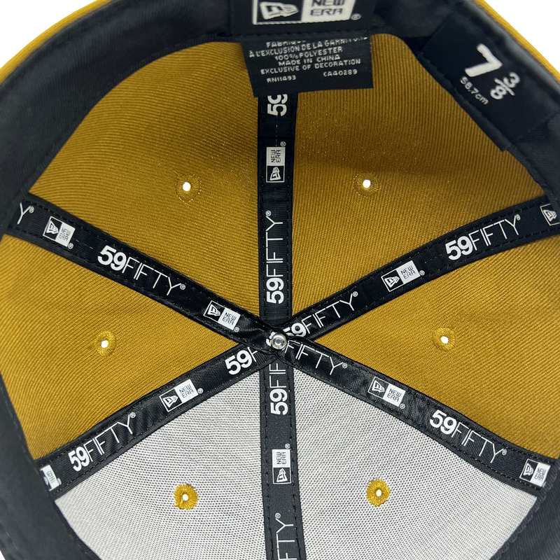 Close-up inside crown view of New Era 9FIFTY gold fitted cap with black New Era wordmark on repeat on taping.