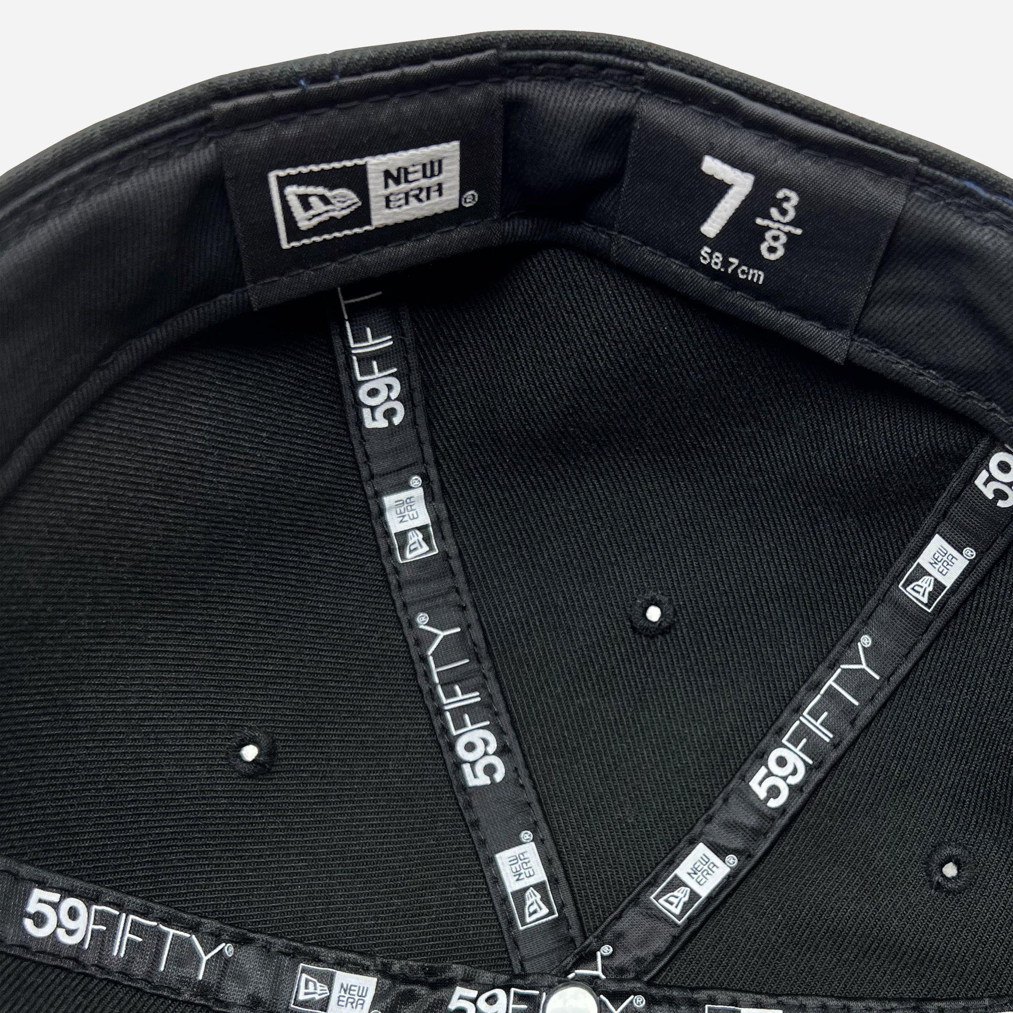 View of inside the crown of New Era 9FIFTY fitted black cap with black New Era striping.