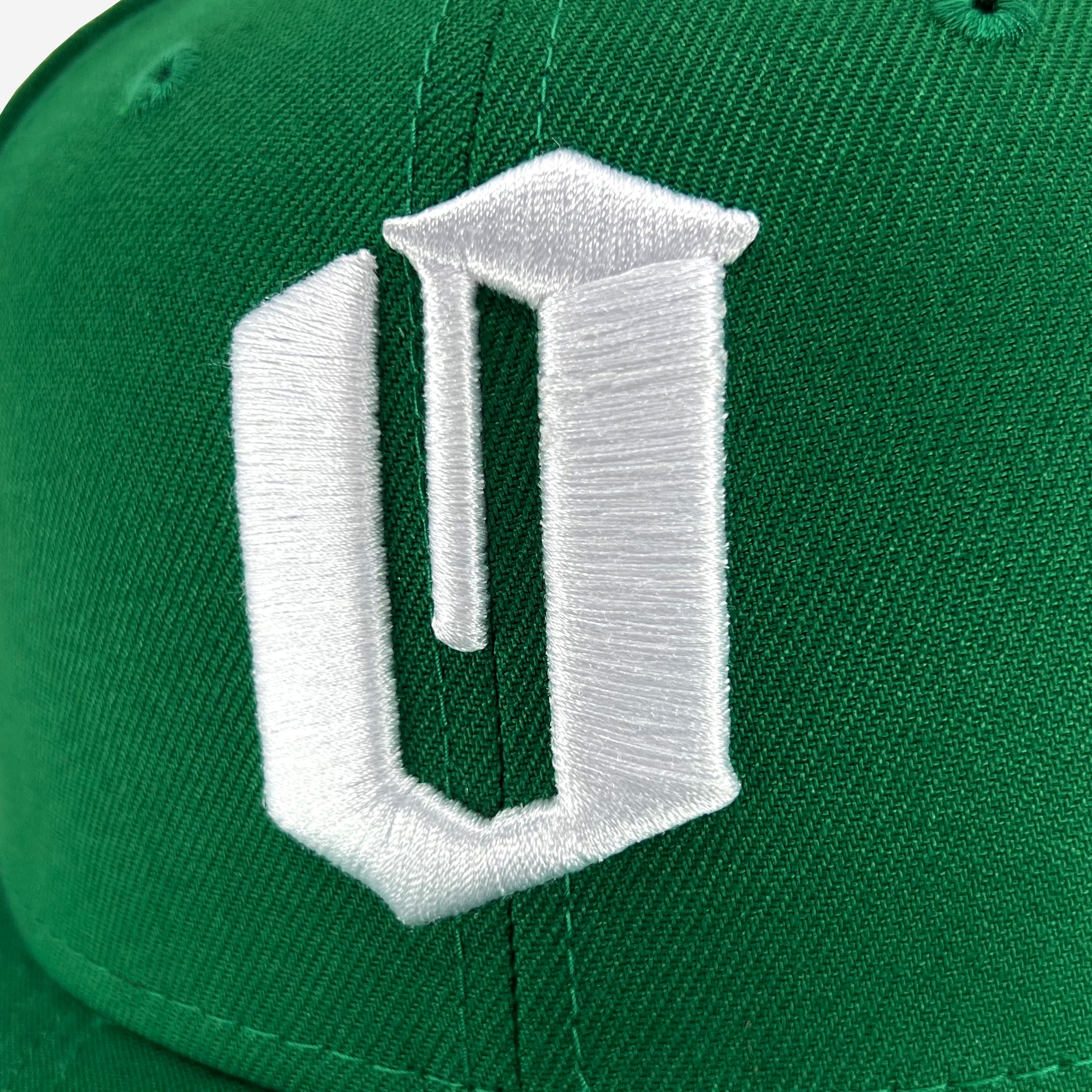 Close up of white embroidered O for Oakland on kelly green New Era cap.