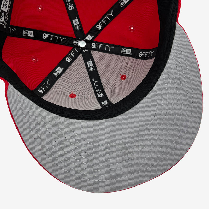 View of inside the crown of New Era 9FIFTY red cap with red crown, grey undervisor and black New Era striping.