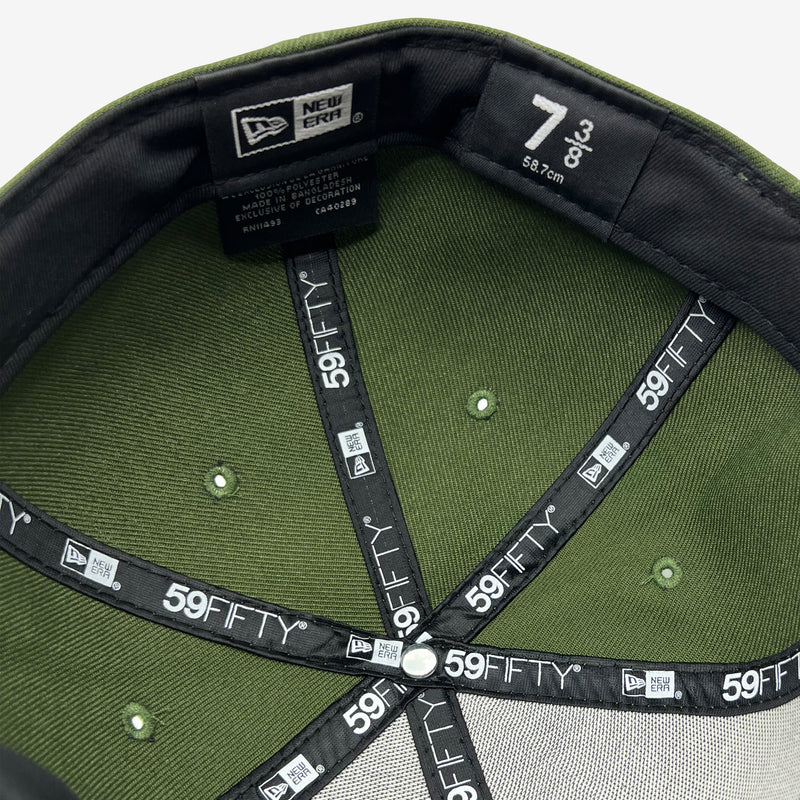 Green inside the crown of a green cap with black taping with 9FIFTY New Era wordmarks on repeat.