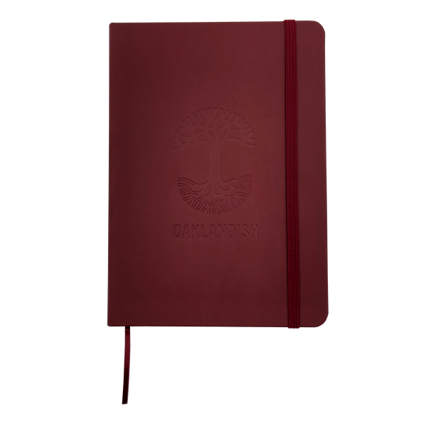 Top view of red Oaklandish journal notebook elastic closure and bookmark with Oakalndish tree logo and wordmark embossed on the cover.