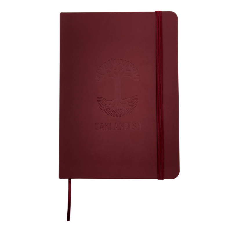 Top view of red Oaklandish journal notebook elastic closure and bookmark with Oakalndish tree logo and wordmark embossed on the cover.