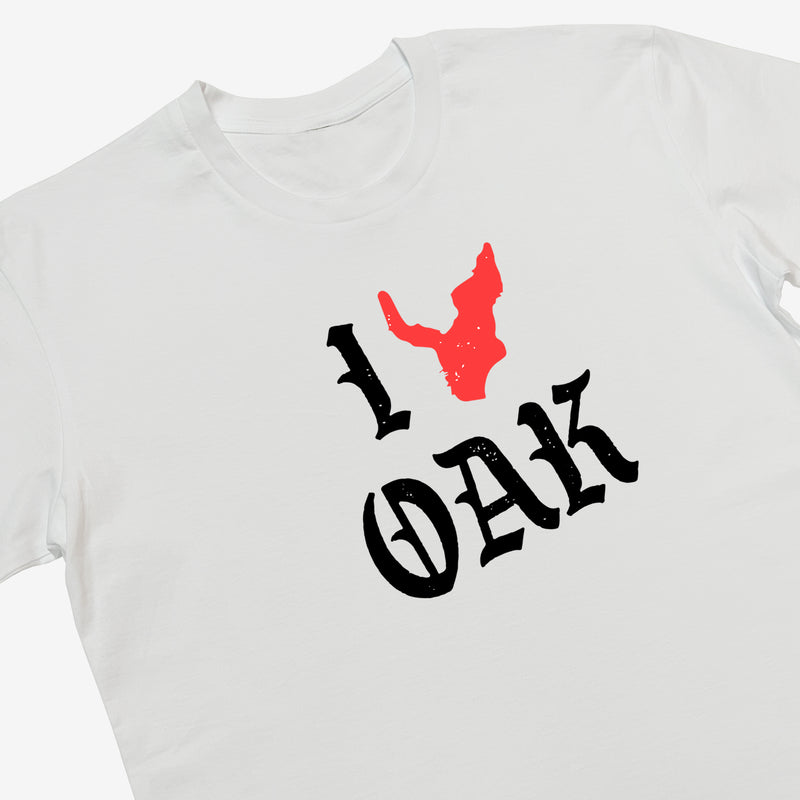 Close-up of a white t-shirt with ”I Oak” in black font and a red map of Oakland replacing the heart between I and Oak.