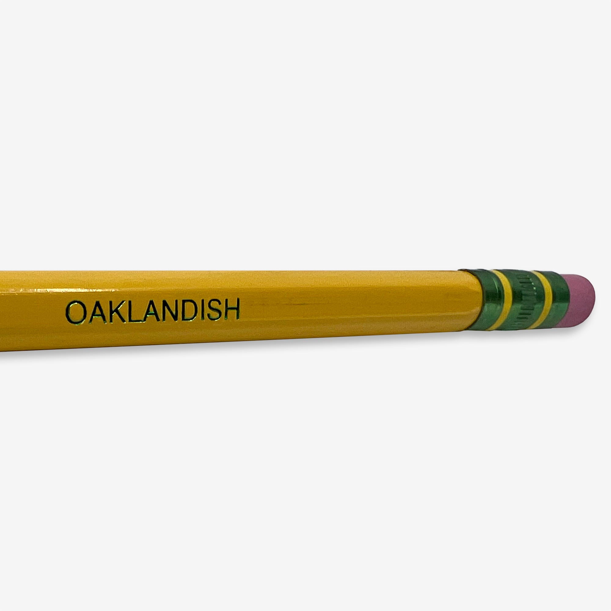 Close up of Oaklandish wordmark on the side of yellow Ticonderoga No. 2 hex pencil with three green stripes under the pink eraser.