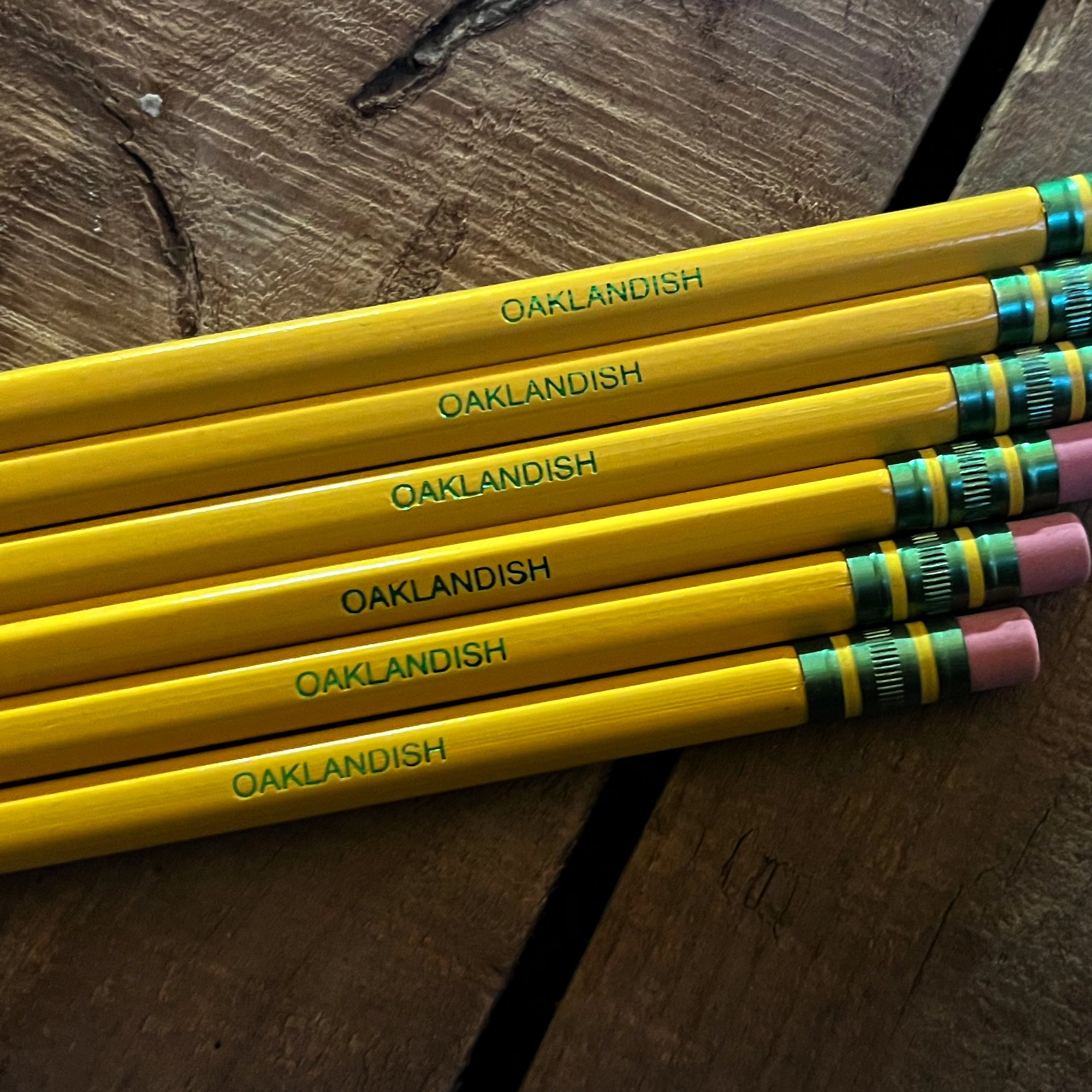 Close up of 6 yellow Ticonderoga No. 2 hex pencils with Oaklandish wordmark on the side on outdoor wood deck.