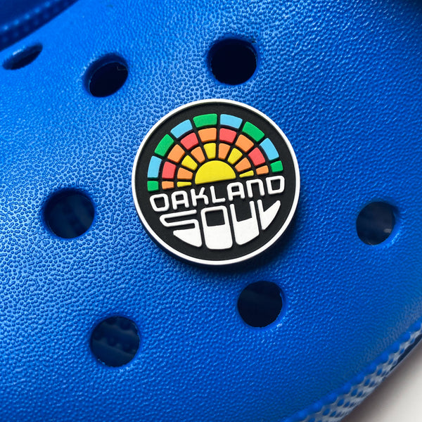 Plastic shoe charm of full-color Oakland Soul logo on blue shoe.