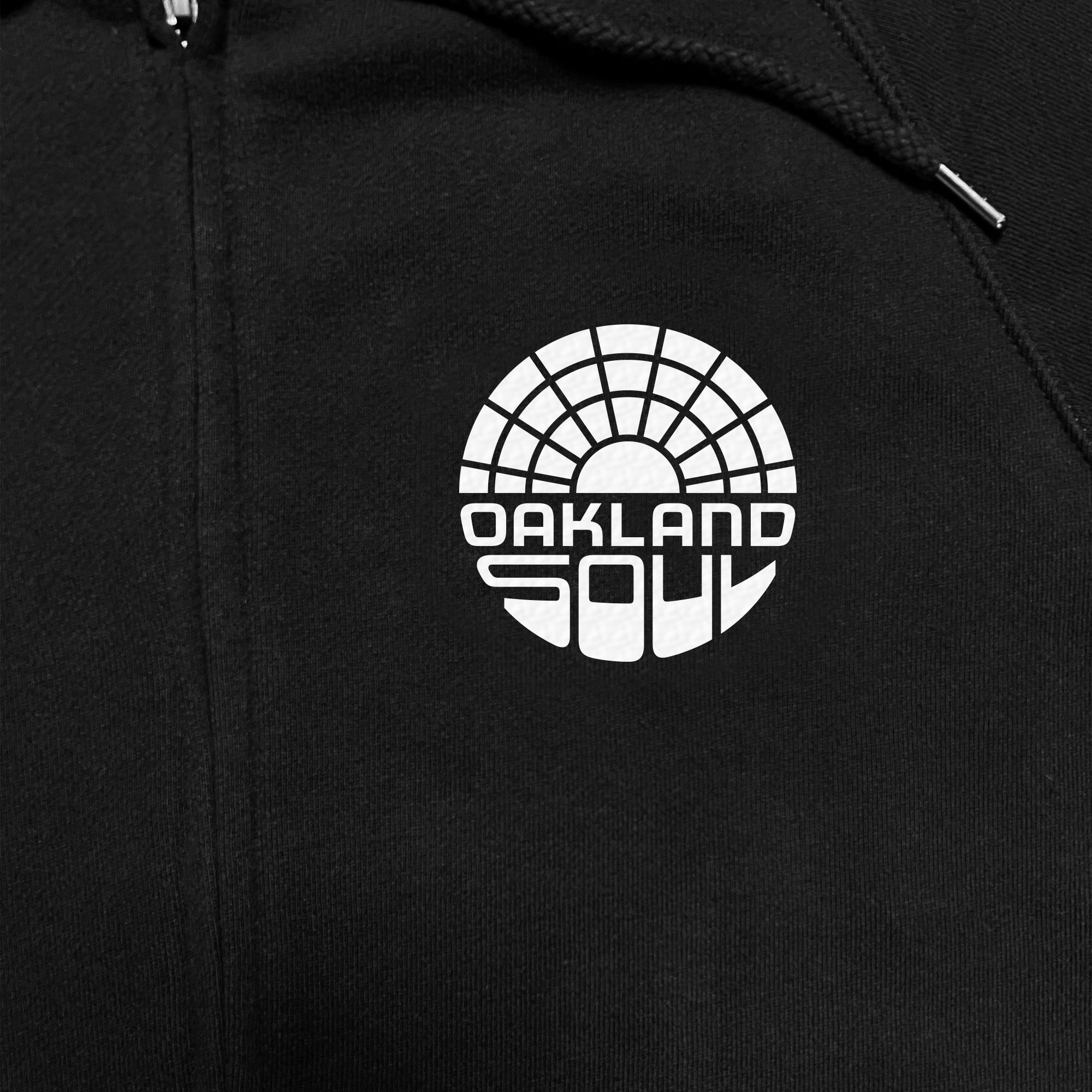 Close up of white Oakland Soul logo on a black zip hoodie.