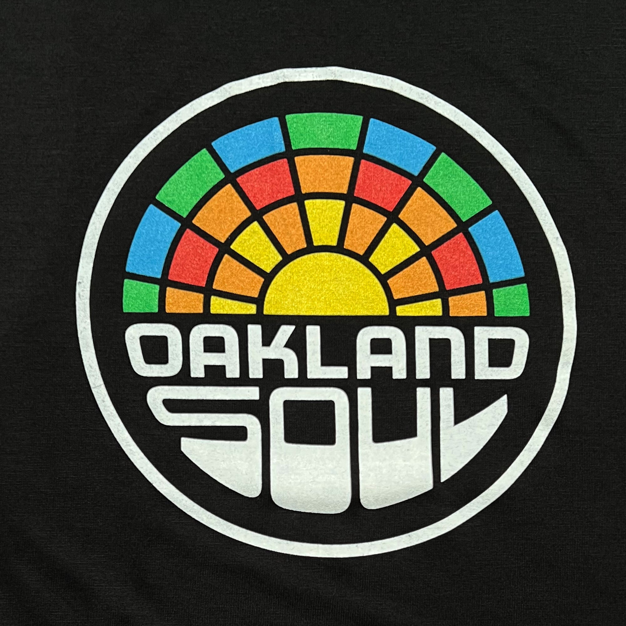 Close up of a full-color Oakland Soul logo on the front of a black cotton tank top.