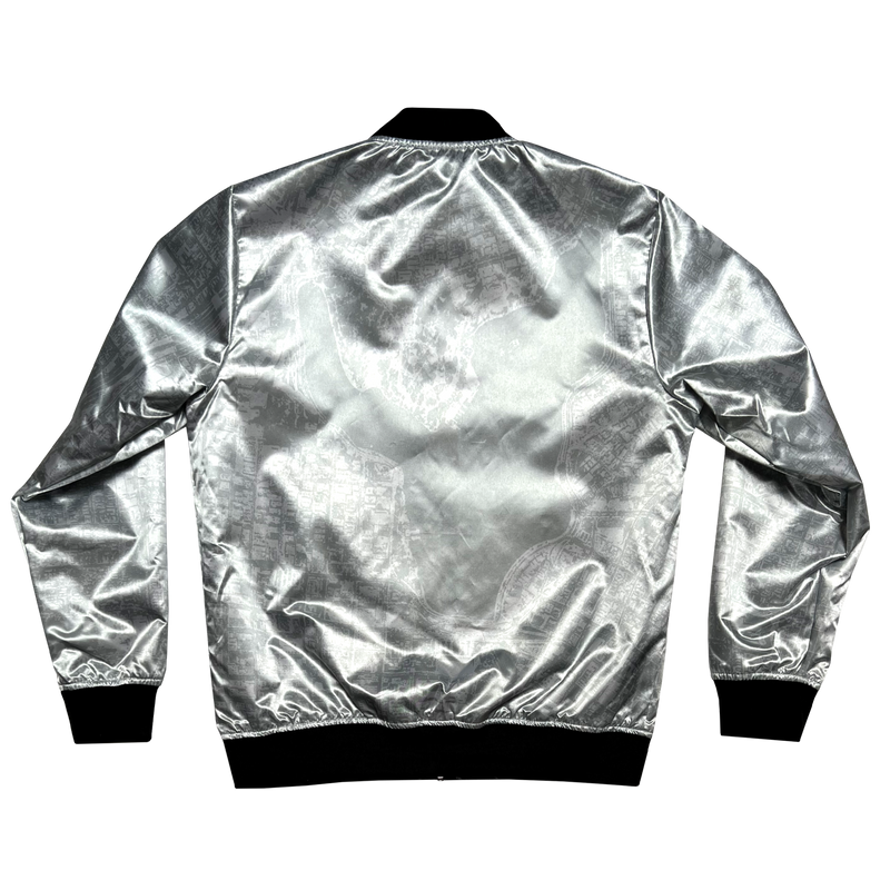The back of a silver reverse side of a satin jacket, imprinted with an aerial map of Oakland with black ribbing at the collar, cuff, and waistband.