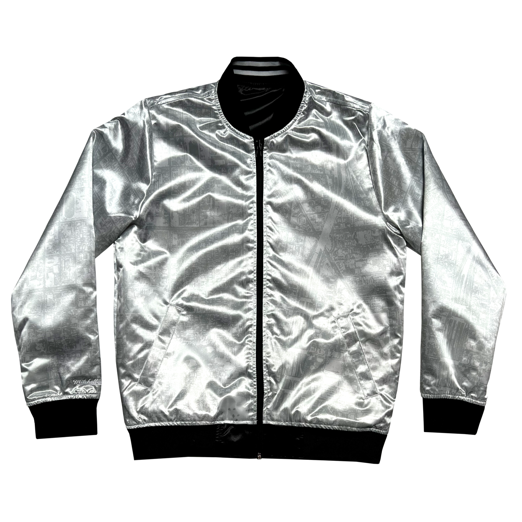 The Mitchell & Ness x Oaklandish Reversible Satin Jacket features a shiny silver exterior with a metallic sheen, black zipper, long sleeves, and two front pockets. Black collar, cuffs, and hem add contrast to the Oaklandish-inspired design.