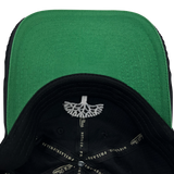 Detailed close-up of green undervisor and taping inside the crown of a black Mitchell & Ness dad cap.