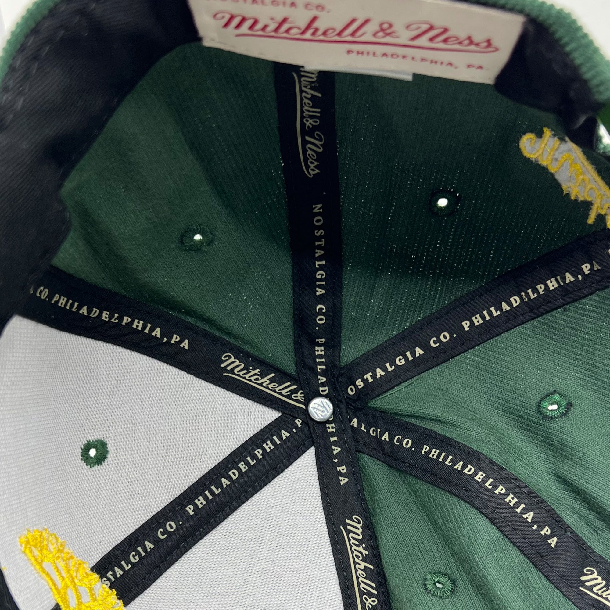 Detailed close up of Mitchell & Ness taping inside crown of green corduroy Oaklandish x Mitchell & Ness cap..