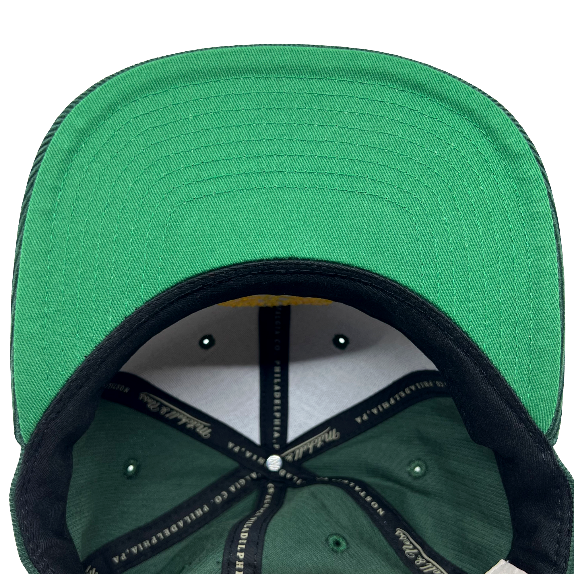 Detailed close-up of green undervisor and taping inside the crown of an Oaklandish x Mitchell & Ness cap.