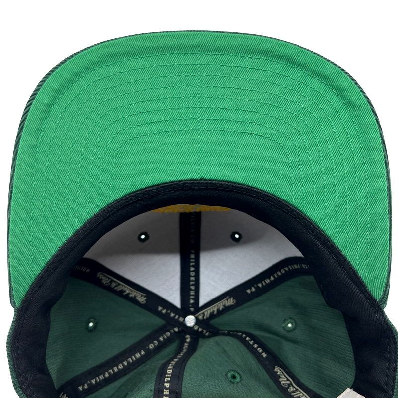 Detailed close-up of green undervisor and taping inside the crown of an Oaklandish x Mitchell & Ness cap.