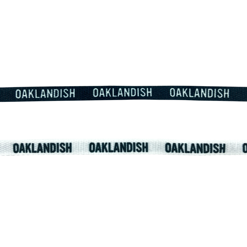 Two shoelaces one white and one black with OAKLANDISH wordmark on repeat.