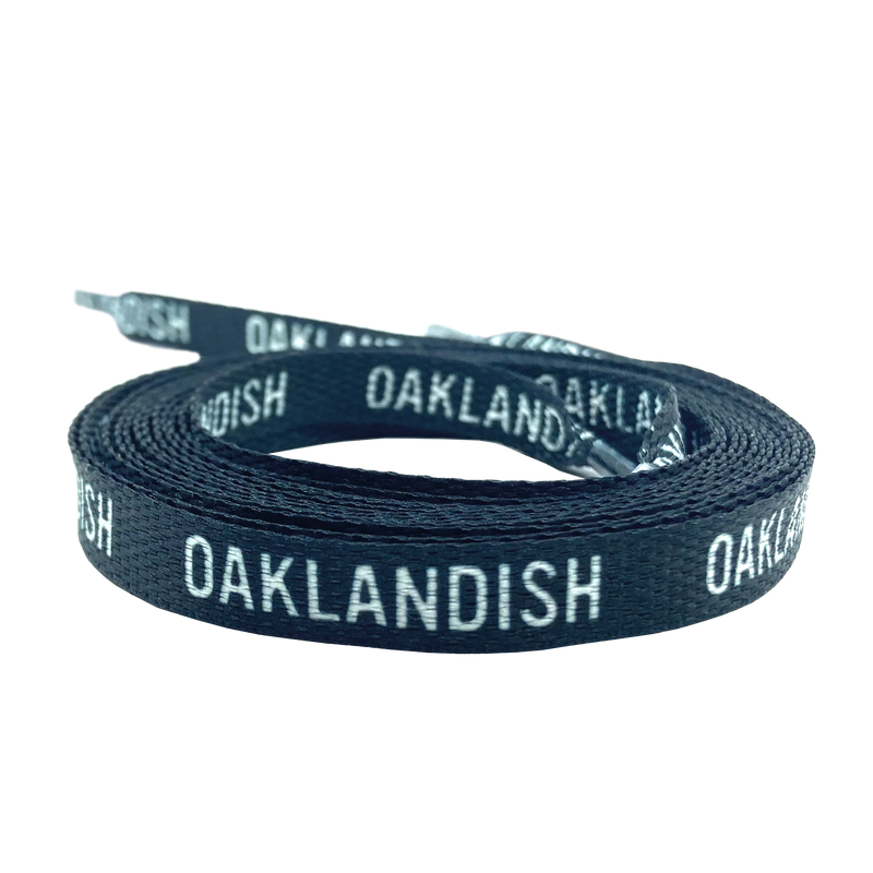Two rolled up black shoelaces with white OAKLANDISH wordmark on repeat.
