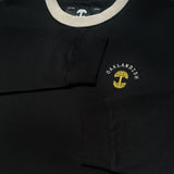 Close-up of embroidered gold Oaklandish tree logo, white wordmark on the chest of a black long-sleeve t-shirt.