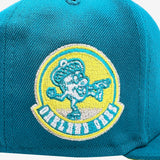 Close-up of Oakland Oaks acorn logo on the back of teal New Era fitted cap.