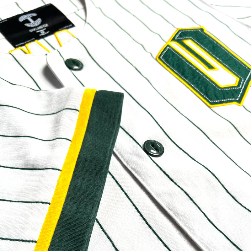 Close-up of green and gold O for Oakland applique on the chest, and green and yellow sleeve trim on a white baseball jersey.