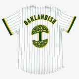 Backside of white baseball jersey with a large green and yellow Oaklandish tree logo and wordmark applique.
