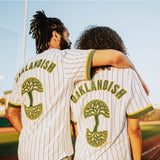 Man with an arm on woman’s shoulder, back to camera, in baseball jerseys with large green and yellow Oaklandish tree logos and wordmarks.
