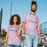Man and women wearing multi-colored speckled soccer shirts with cursive Oaklandish wordmark and black O for Oakland applique in bleachers.