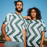 Man and woman wearing soccer jerseys with green and white zig-zag patterns with black Oakland O and Oaklandish tree logos on chest.