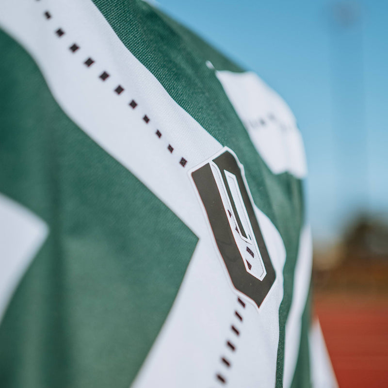 Close-up of black Oakland O on green and white soccer jersey chest.