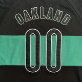 Close-up of OAKLAND 00 applique on a green and black soccer jersey.