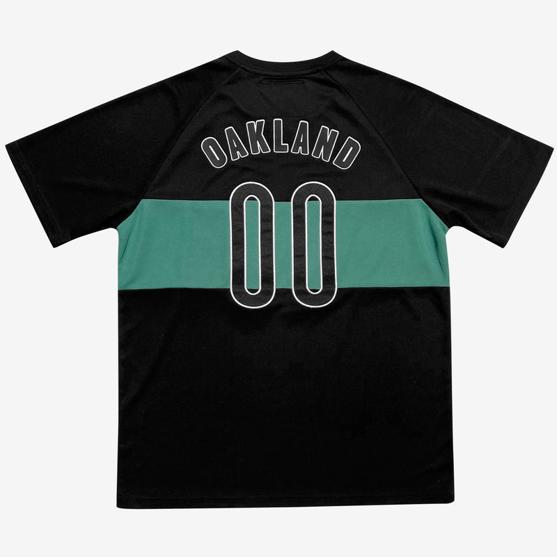The backside of a black soccer jersey with a green stripe and OAKLAND 00 applique.
