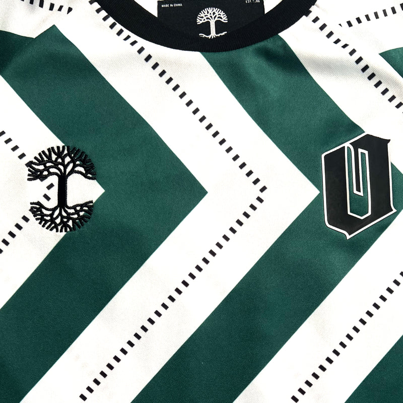 Close-up of black Oakland O and Oaklandish tree logo on green and white soccer jersey chest.