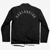 Backside of black nylon coaches jacket with white Oaklandish wordmark logo.