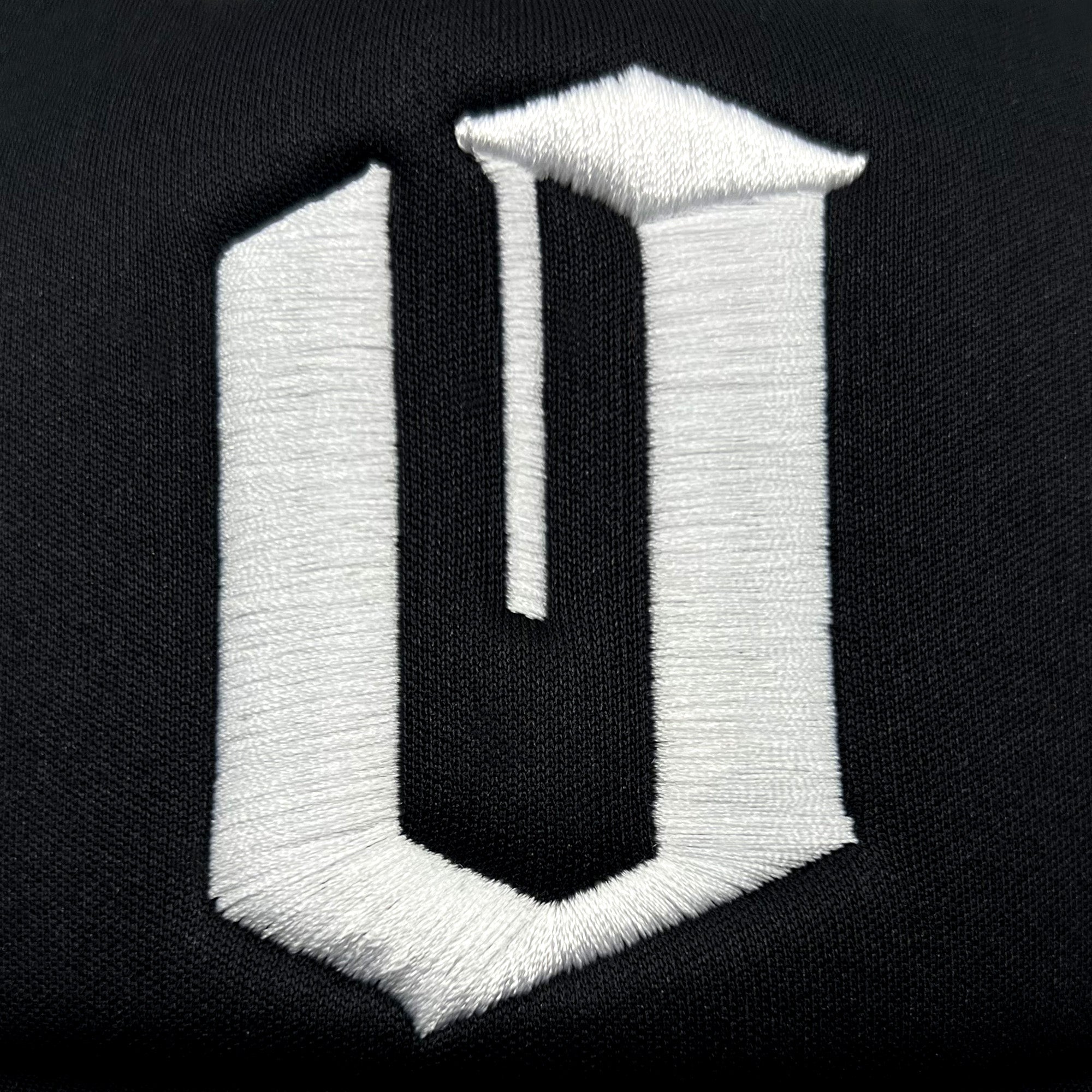 Detailed close-up of embroidered white Official O logo on a black Mitchell & Ness truckers cap.