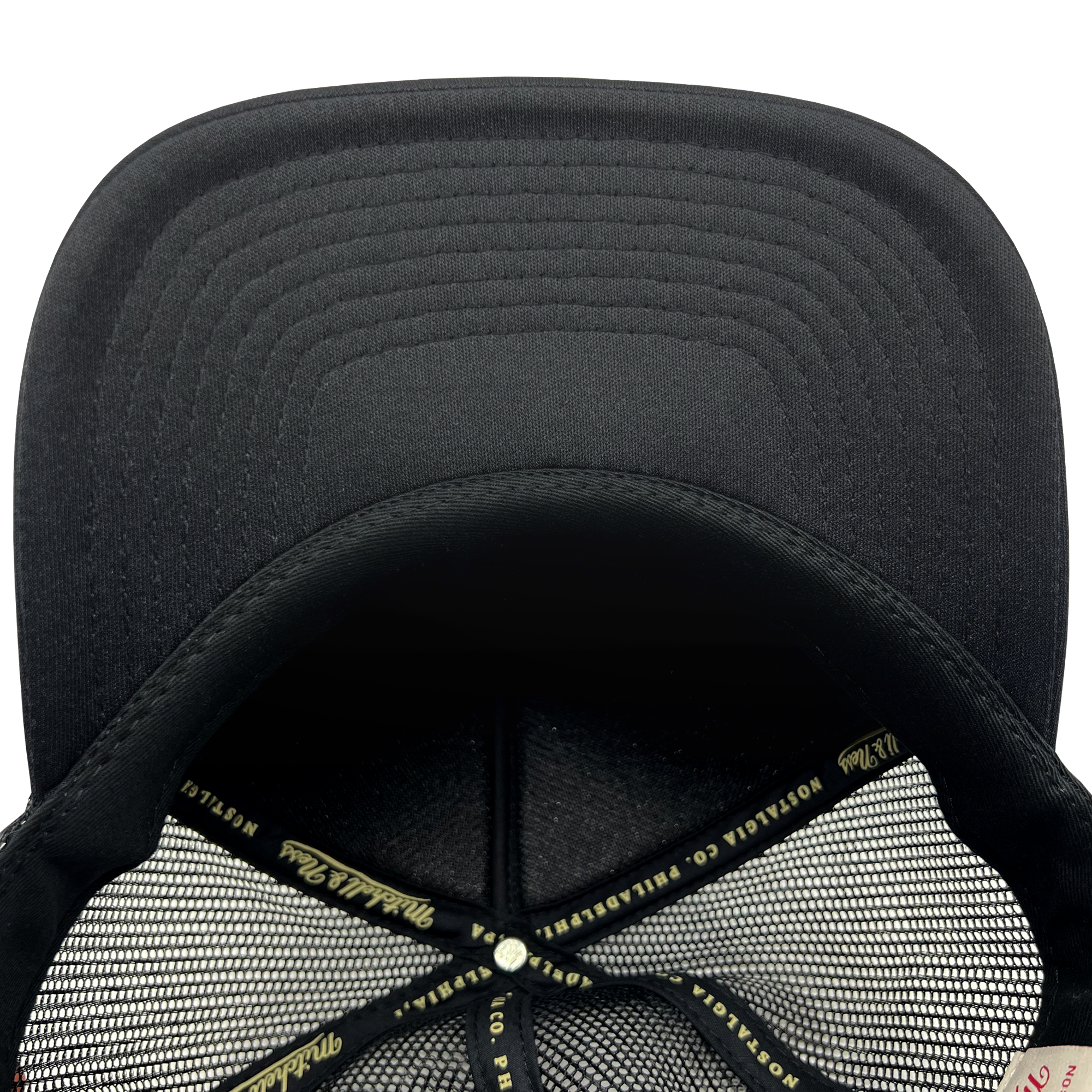 Detailed close-up of black undervisor and taping inside the crown of a black Mitchell & Ness truckers cap.