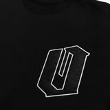 Detailed close-up of black and white O for Oakland applique patch on the chest of a black crewneck sweatshirt.