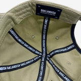 Inside of khaki dad hat crown with ‘OAKLANDISH’ wordmark on black striping and Oaklandish patch.
