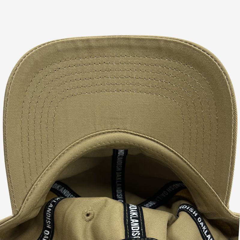 Under brim angle and inside of khaki snapback hat crown with ‘OAKLANDISH’ wordmark on black striping