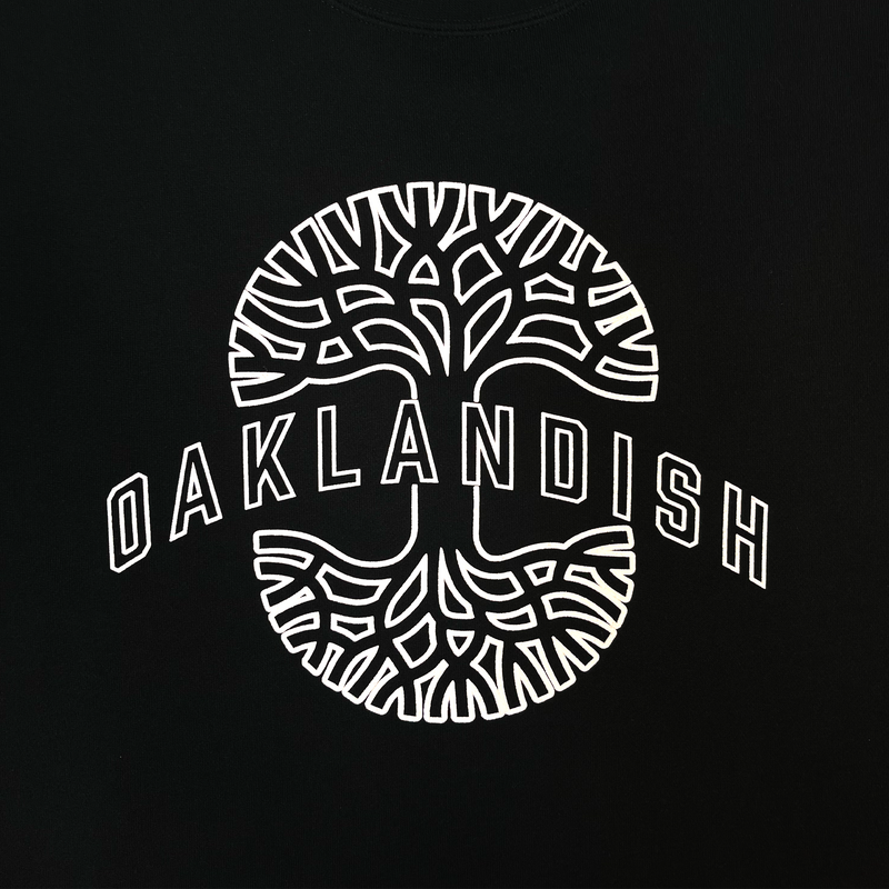 Full close up of Oaklandish wordmark on top of Oaklandish tree logo in white puff ink on black crewneck sweatshirt.