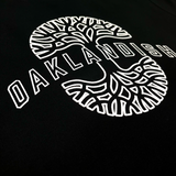Close up image of Oaklandish wordmark on top of Oaklandish tree logo in white puff ink on black crewneck sweatshirt.