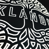 Detailed close up image of Oaklandish wordmark on top of Oaklandish tree logo in white puff ink on black crewneck sweatshirt.
